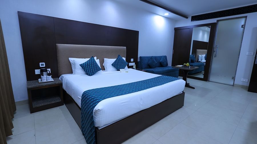 Image of Premium room at Hotel Amar with a bed, side table and wardrobe.