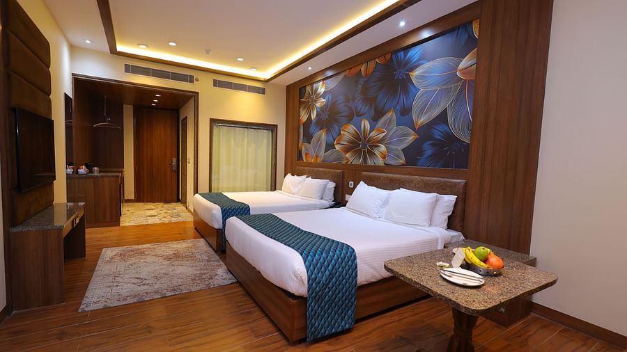 Side angle image of a Suite at Amar Hotel with two beds, table and a painting