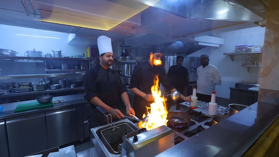 Side angle image of chefs cooking with high flame the anam restaurant of Hotel Amar