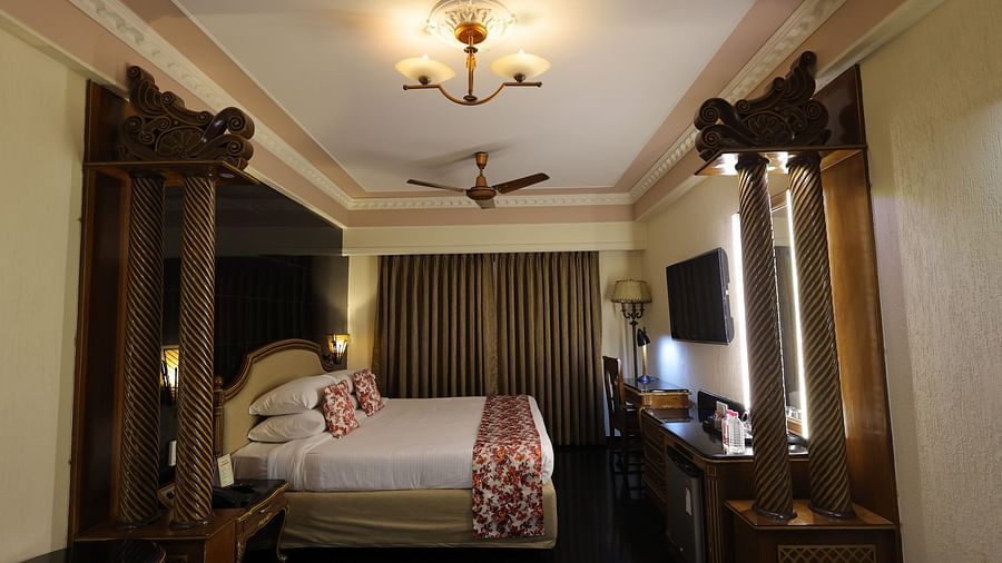 Close up  image of Premium room at Hotel Amar with a bed, table and long curtains.