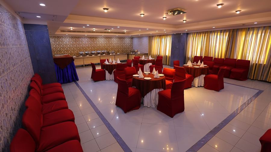 Overview image of Dewaane-e-khas hall of Hotel Amar with red chairs and cluster seating arrangement 