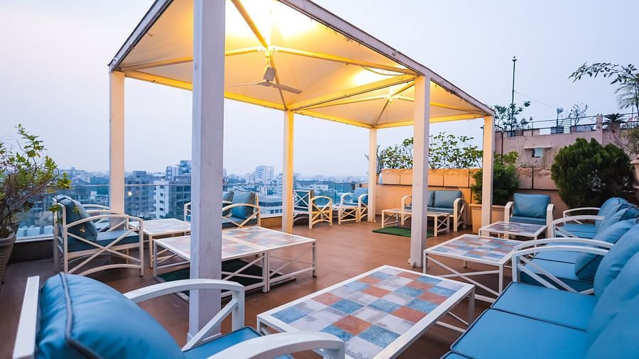 An outdoor dining setup at Hotel Ashok Nagpur featuring cushioned chairs and tables arranged on a rooftop or terrace during the evening.