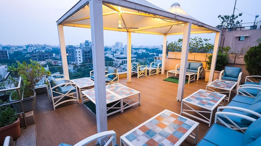 An outdoor dining setup at Hotel Ashok Nagpur featuring cushioned chairs and tables arranged on a rooftop or terrace.
