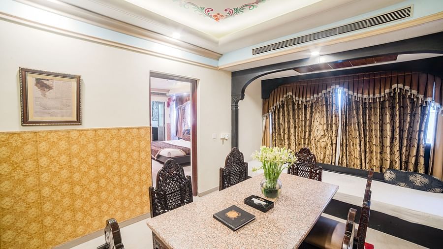Queen Room featuring a long table with chairs, and a dark curtain backdrop. - Hotel Ashok Nagpur