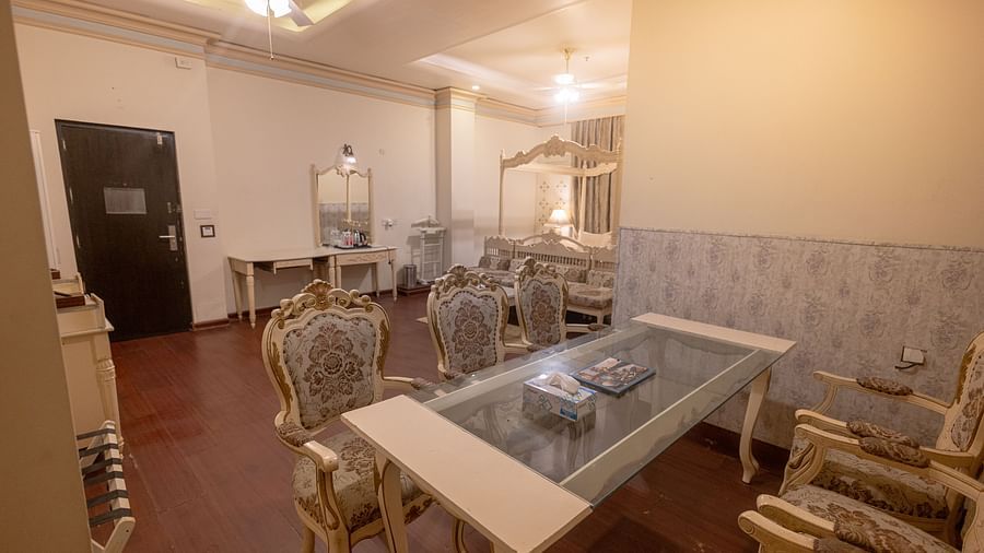 King Suite featuring a glass-topped coffee table and upholstered chairs with wooden frames.- Hotel Ashok Nagpur
