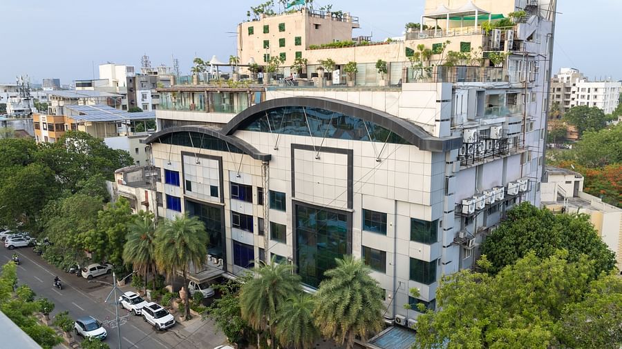 The exterior of Hotel Ashok Nagpur, featuring its architecture, surrounding greenery, and a couple of cars parked nearby.