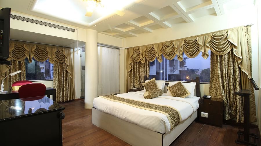 A Deluxe Room with a large bed placed in front of the TV at Hotel Ashok Nagpur.