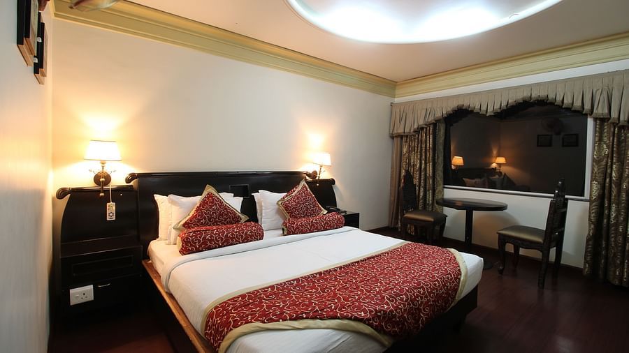Deluxe Room featuring bed next to seating area at Hotel Ashok Nagpur.