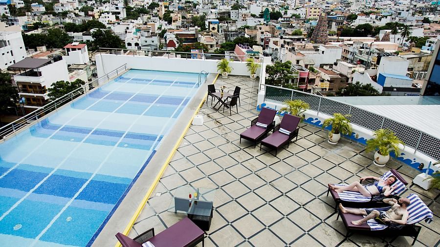 Rooftop Pool with lounging chairs during the day at Hotel Atithi - TGI Grand, Pondicherry