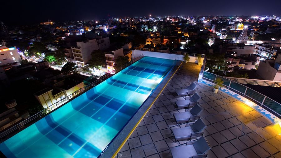 Rooftop Pool with lounging chairs during the night at Hotel Atithi - TGI Grand, Pondicherry