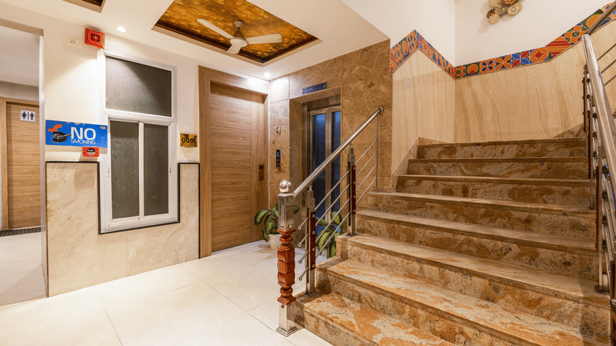 Staircase with stone treads and a steel railing leading to upper floors next to a lift at Hotel Corporate Suites