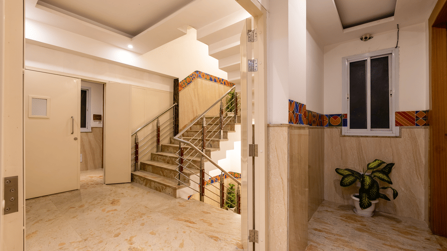 Lobby featuring a marble staircase, a potted plant, and an open fire exit door leading to the upper guest floors at Hotel Corporate Suites