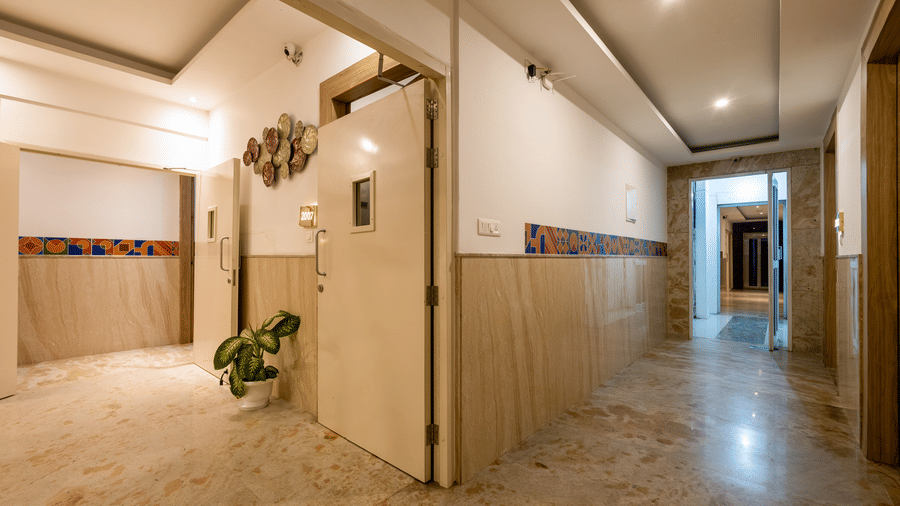 Lobby segment featuring sleek, cream-coloured panelled walls, marble flooring, and a decorative circular wall accent near the room access corridor at Hotel Corporate Suites