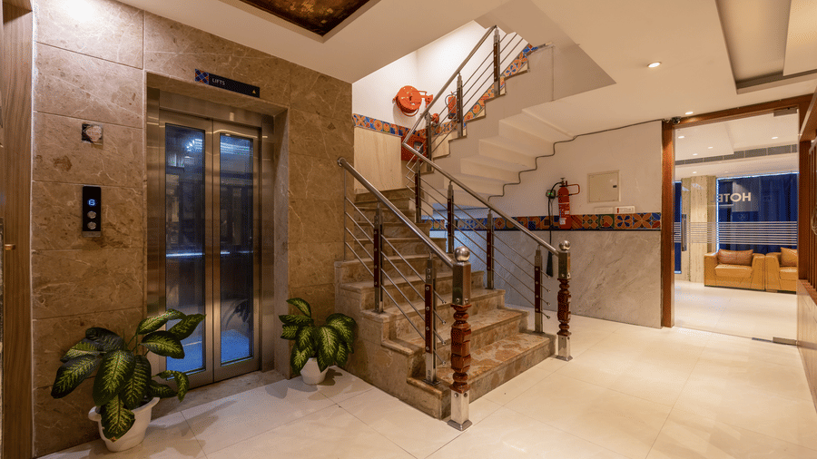 Lobby of Hotel Corporate Suites featuring a lift, a fire extinguisher, and a stone staircase accented with colourful patterned tiles