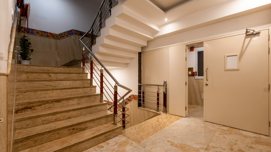 Corridor at Hotel Corporate Suites featuring a staircase with steel railings and warm lighting
