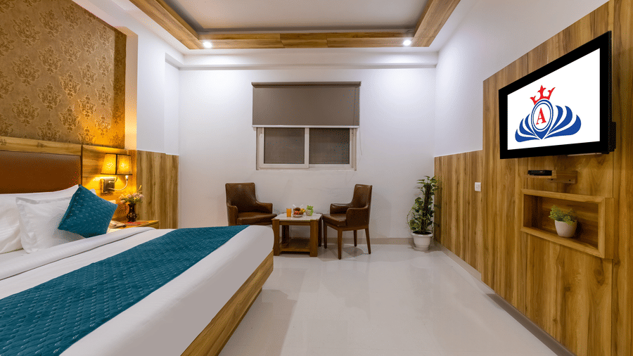 A well-appointed Deluxe Room showcasing a stylish headboard with patterned wallpaper facing a mounted TV at Hotel Corporate Suites