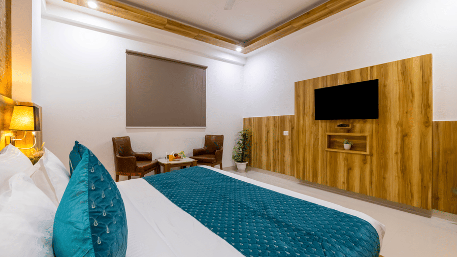Deluxe Room featuring dark wood finishes, crisp linens, and a wall-mounted television in the front at Hotel Corporate Suites