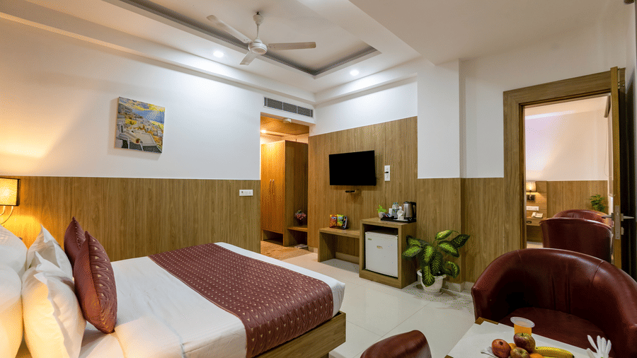 Executive Room at Hotel Corporate Suites featuring a plush bed facing the TV mounted on the wall with tea and coffee maker and minibar below it on the counter