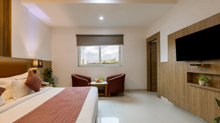 Executive Room at Hotel Corporate Suites featuring a bed facing the TV mounted on the wall and a seating space for 2 by the window
