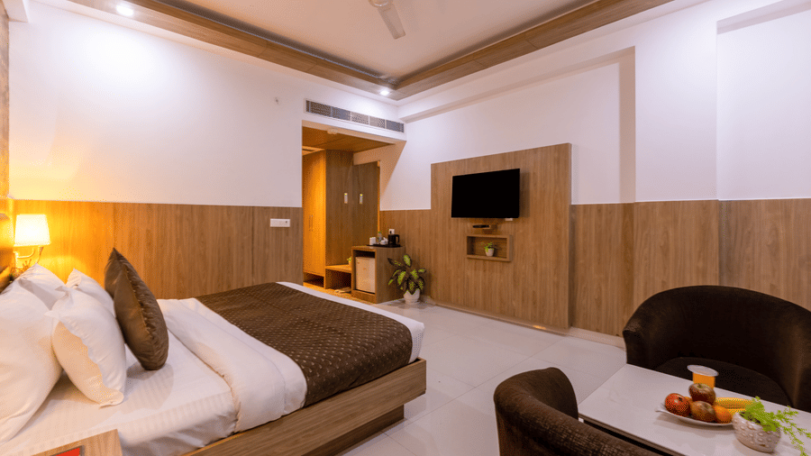 Executive Room at Hotel Corporate Suites featuring a plush bed facing the TV mounted on the wall and a seating space by the bed for 2