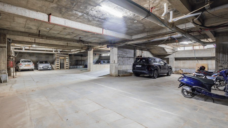 Parkign space at Hotel Corporate Suites featuring concrete ceilings and several parked vehicles