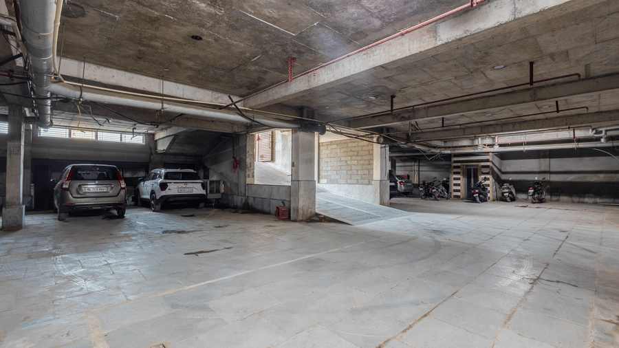 Parking space at Hotel Corporate Suites displaying concrete pillars and several parked vehicles neatly
