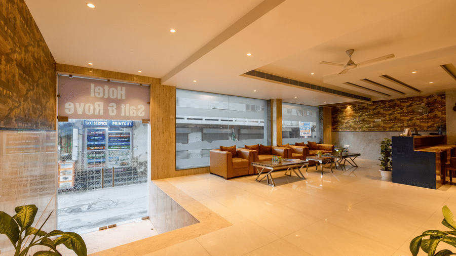 Lobby at Hotel Corporate Suites featuring a reception desk, tan sofas for guest seating, large glass windows, and a neat ceiling design with soft recessed lights