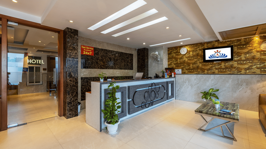 Reception area featuring a dark stone-clad desk, modern recessed lighting, and a comfortable seating lounge at Hotel Corporate Suites