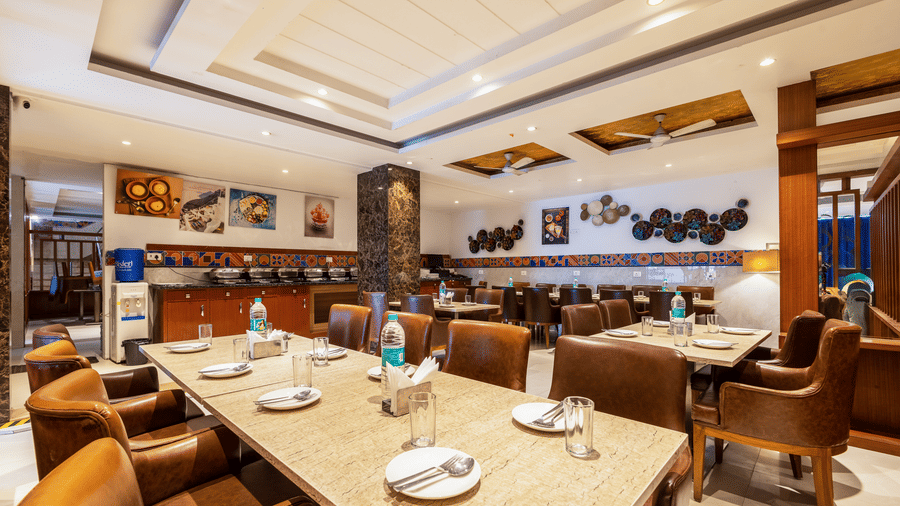 The Curry House featuring multiple tables set for dining with leather chairs and artistic wall decor at Hotel Corporate Suites