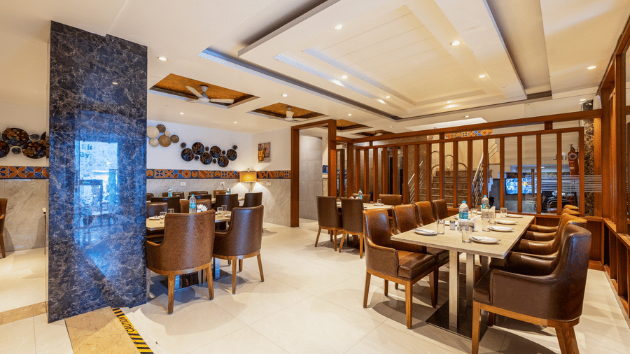 Interior of The Curry House featuring clean, neutral tones, comfortable leather seating, and decorative wooden partitions at Hotel Corporate Suites