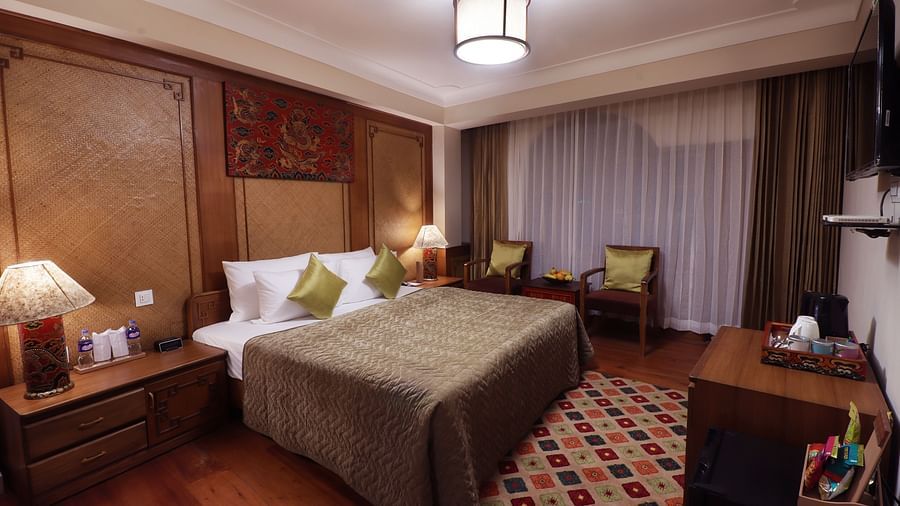 A cozy bedroom with a plush bed, a cozy armchair, and a window Hotel Denzong Shangrila Lords Inn