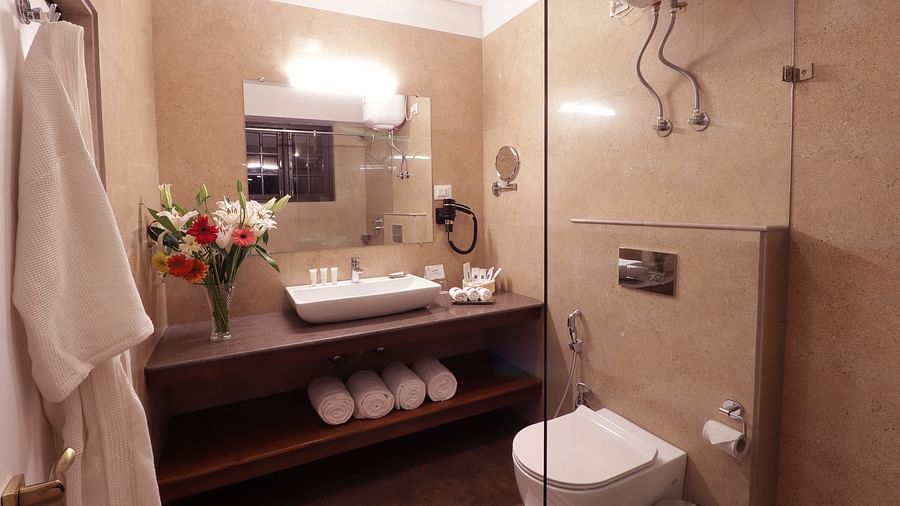 A clean and modern bathroom with a large shower, and a vanity with a mirror and sink -Hotel Denzong Shangrila Lords Inn