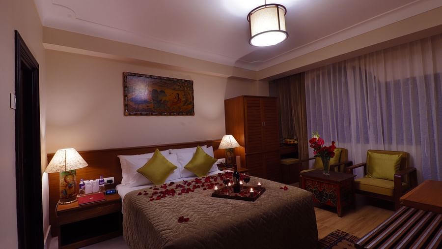A cozy and inviting bedroom with a decorated bed, a fireplace, and a window - Hotel Denzong Shangrila Lords Inn