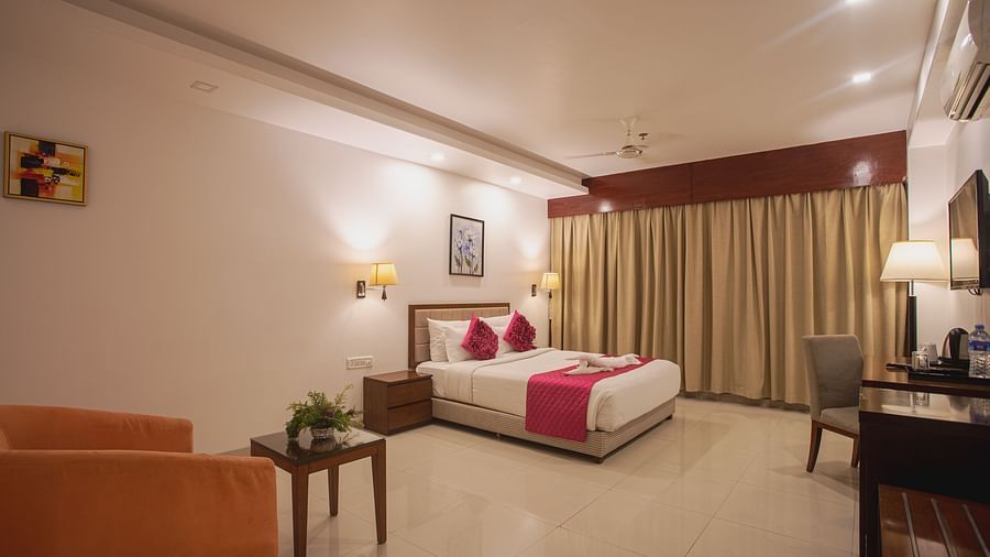 Comfortable hotel room at Diamond Palace Lords Plaza with a double bed, seating area, work desk, and a large window.