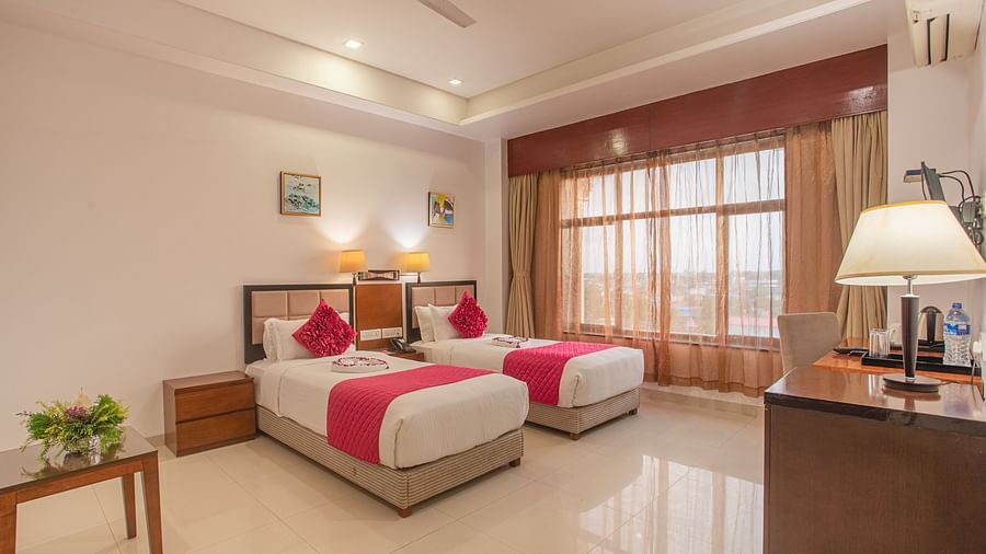 Bright twin room at Diamond Palace Lords Plaza with two single beds featuring pink accents, a work desk, and a small table.