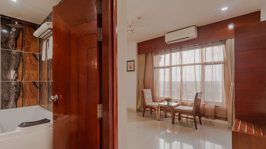 Hotel suite at Diamond Palace Lords Plaza with a visible bathroom and a separate dining area with a table and chairs.