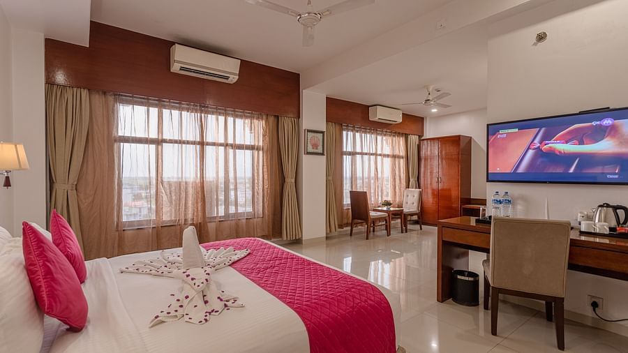 Spacious hotel suite at Diamond Palace Lords Plaza with a double bed, work desk, TV, and a separate seating area by the windows.