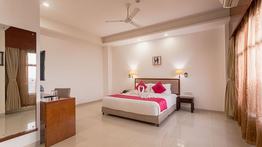 Well-lit hotel room at Diamond Palace Lords Plaza with a double bed featuring pink accents and a spacious layout.