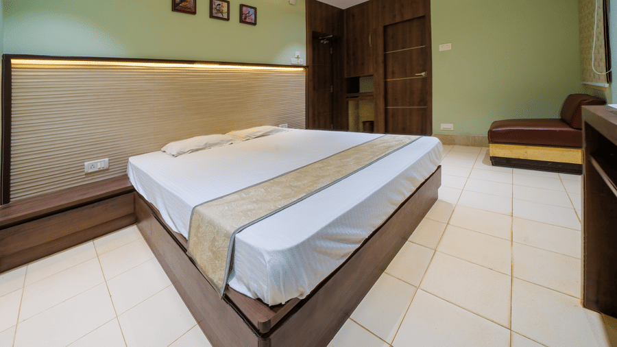 Spacious room with a double bed, a wooden wardrobe, a seating area, and tiled flooring – Hotel Dolphin Puri