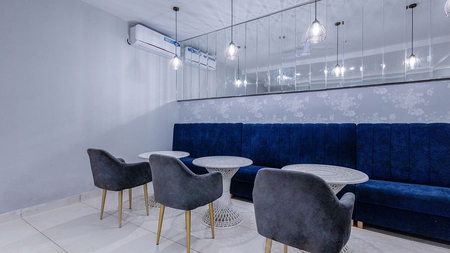 corner view shot of the restaurant with three round tables with a huge blue couch in front of it - Hotel Downtown17, Chandigarh