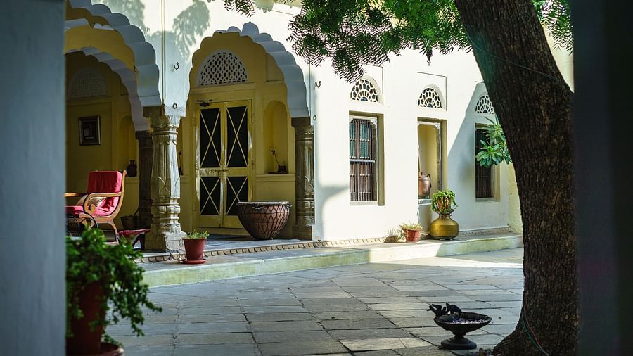 A serene courtyard at Fort Barli, with arched doorways and a large tree, captures the fort's tranquil atmosphere.