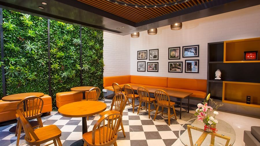 a room with large windows with views of trees and circular tables with chairs around them - Hotel Fountain Tree By TGI - JP Nagar, Bangalore
