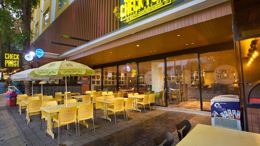 an outdoor restaurant with umbrellas mounted on the tables to provide shade - Hotel Fountain Tree By TGI - JP Nagar, Bangalore