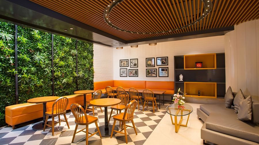 a room with large windows with views of trees and circular tables with chairs around them - Hotel Fountain Tree By TGI - JP Nagar, Bangalore