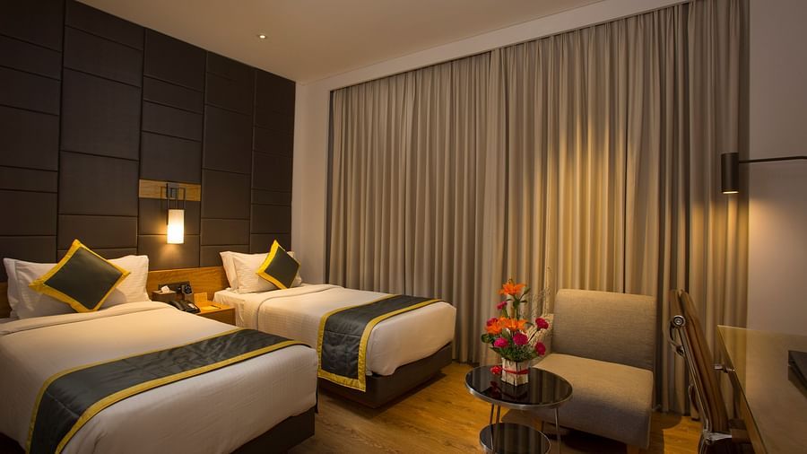 a bedroom with two single beds and a sofa - Hotel Fountain Tree By TGI - JP Nagar, Bangalore