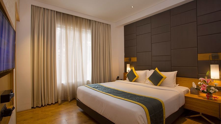 view of a bedroom with a large bed facing a television and two side drawers, one on each side of the bed - Hotel Fountain Tree By TGI - JP Nagar, Bangalore