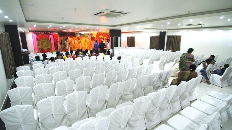 Swathi Hall with chairs neatly arranged and a decorated pulpit in front at Hotel Green Apple