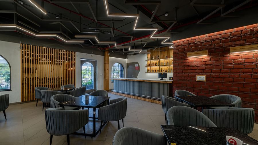 A lounge and bar space at Hotel Highway King, Bagru, featuring modern chairs, ambient lighting, and brick wall accents.