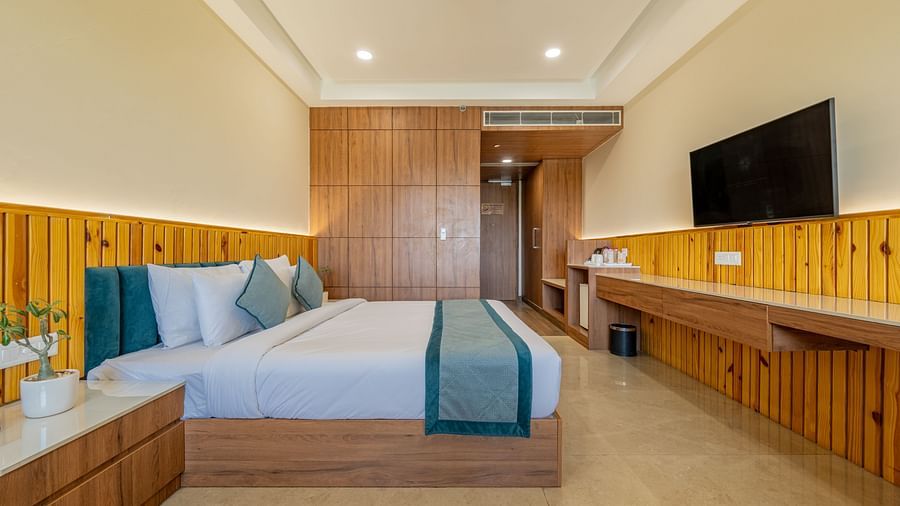 Modern room with king bed, flat-screen TV, and wooden decor accents in an executive king room at Hotel Highway, Bagru.