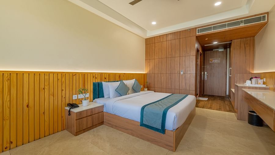 Elegant bedroom with ceiling fan, side table, and wardrobe setup in an executive king room at Hotel Highway, Bagru.